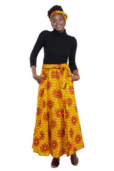 Woman wearing African print long maxi skirt in bold Ankara fabric, styled for cultural events, weddings, or everyday elegance.